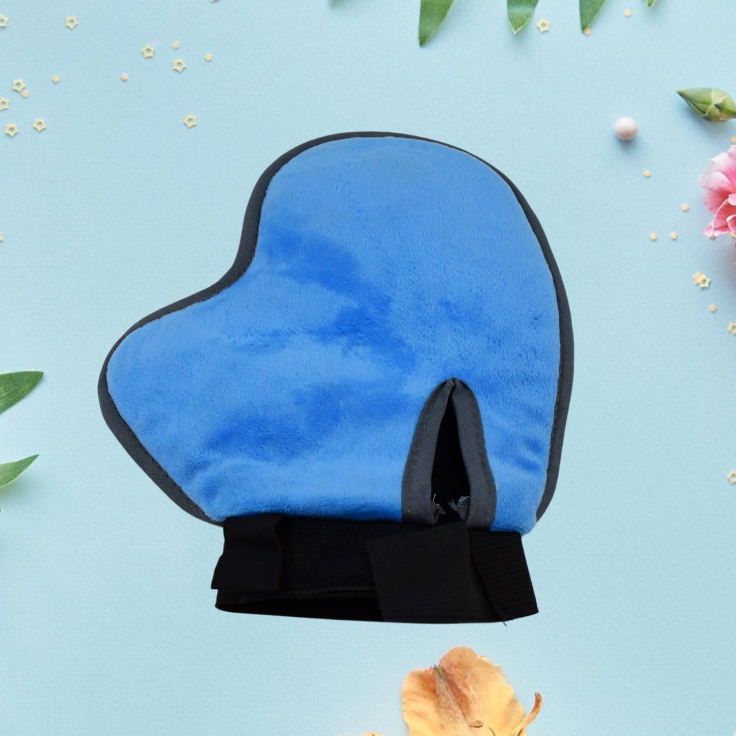 Pet grooming glove deshedding tool mitt for dogs and cats, blue soft mitt against a floral background.